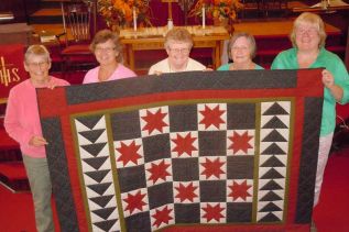 L-r, Trinity quilters Ann McDougall, Bonnie Brown, Beth Abbott, Myriel York and Debbie Lovegrove hold up the Frontenac Star quilt, one of three quilts that will be raffled off at The Trinity Quilters Heritage Quilt Show on October 17 at Trinity United Church in Verona  